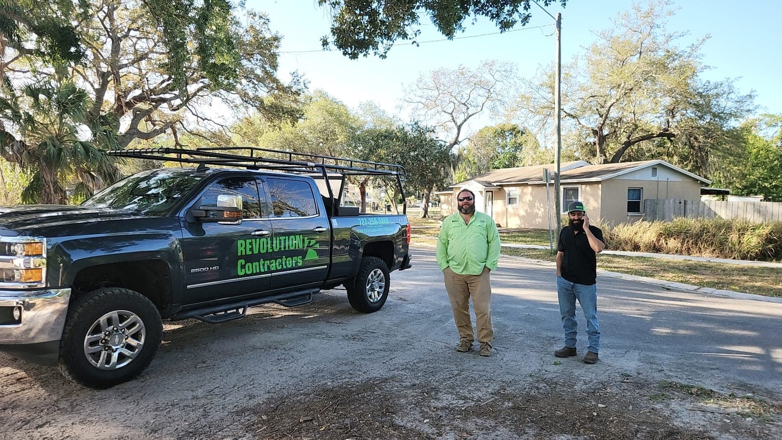 Revolution Contractors truck parked in a Pinellas County residential neighborhood with two crew members